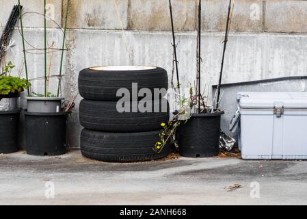 Alte Reifen und alte Räder türmten sich an einer Ecke einer Garage auf. Stockfoto