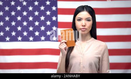 Zuversichtlich asiatische Frau, Pass gegen USA-Flagge im Hintergrund, Migration Stockfoto