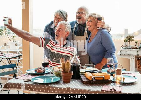 Happy Senioren Freunde unter selfie mit Mobile Smartphone Kamera zum Abendessen auf der Terrasse - Rentner spaß essen und trinken Rotwein Stockfoto