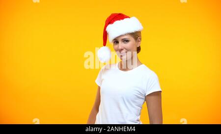 Attraktive junge Frau in santa hut suchen Kamera auf orangem Hintergrund, party Stockfoto
