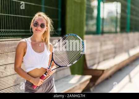 Ziemlich lächelnden jungen Frau in Weiß Top und Shorts Tennis spielen Stockfoto