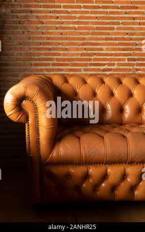 Braunes Leder Sofa Sitz mit Red brick wall Hallenbad gemütliche Hintergrund Stockfoto