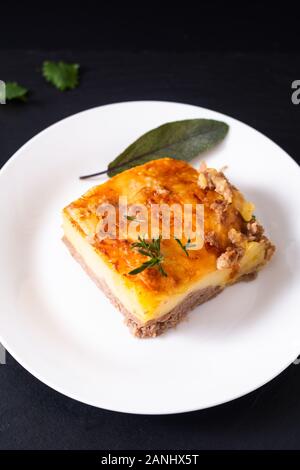 Essen Konzept hausgemachte organische Kartoffelpüree Rindfleisch Auflauf auf weißer Keramik Platte auf schwarzem Schiefer Hintergrund Stockfoto