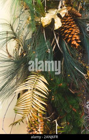 Stilvolle moderne Weihnachtsdekoration mit goldenen Blättern und Kegel an Tannenzweigen. Stockfoto