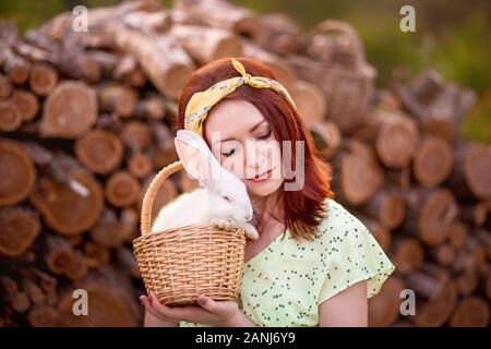 Frau, die süßes kleines Kaninchen im Korb hält. Oster-Weißbrötchen. Stockfoto