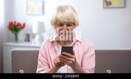 Positive gealterte Frau mit Smartphone, Online Shopping, Social Network chatten Stockfoto