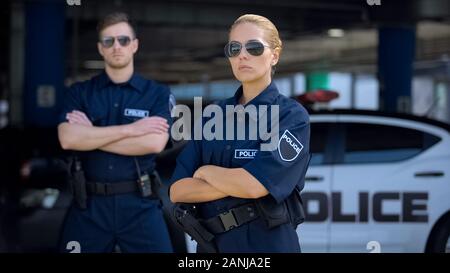 Ernster Mann und Frau Polizeibeamte in Sonnenbrille ständigen Außeneinsatz, Sicherheit Stockfoto