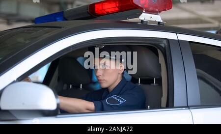 Respektable Polizeioffizier im Hut im Auto sitzen, patrouillieren, um die öffentliche Sicherheit Stockfoto