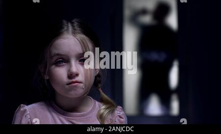 Weinend kleine Mädchen an Kamera Silhouette von alkoholkranken Vater vor der Tür suchen Stockfoto