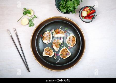 Würzige Aubergine/Aubergine mit Tofu und Gemüserührer, serviert auf einer Keramikplatte mit Essstäbchen. Bambus matt und Dampfgarer mit schwarzem Hintergrund Stockfoto