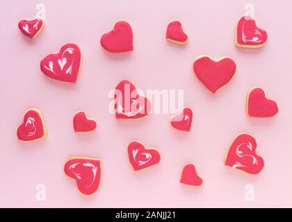 Heart-shaped Cookies in verschiedenen Größen auf einem rosa Hintergrund. Flach. Valentinstag Konzept. Stockfoto