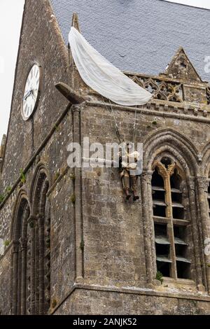 Attrappe des Fallschirmjägers John Steele, der während der alliierten Invasion im zweiten Weltkrieg auf der Spitze der Kirche von Sainte-Mère-Église in der Normandie festsaß Stockfoto