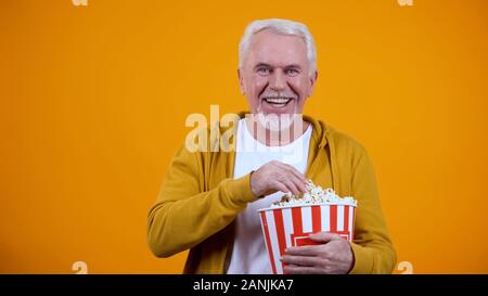 Fröhliche grauhaariger Mann mit Popcorn und Lachen während des Films Stockfoto