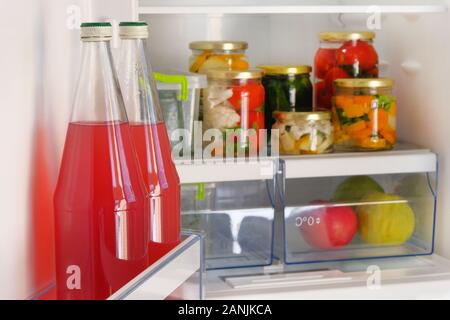 Flaschen mit hausgemachten rote Saft und Gläser verschiedener eingelegtes Gemüse stehen im Kühlschrank. Fermentierte gesunde natürliche Ernährung Konzept. Stockfoto