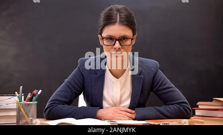 Schweren Kopf Lehrer aggressiv auf die Kamera zu sitzen, Tabelle, Bildung Stockfoto