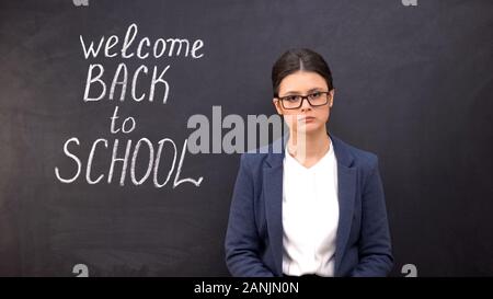 Müde Lehrer stehen in der Nähe der Tafel, willkommen zurück in der Schule Inschrift Stockfoto