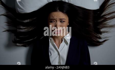Betonte Asian Business Frau im Bett liegen, Angst vor endlosen Büro arbeiten Stockfoto