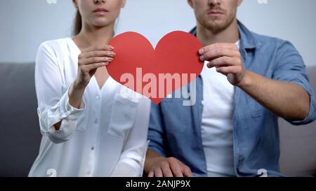 Unglückliches Paar hält Herz aus Papier, Probleme in der Beziehung, Scheidung Risiko Stockfoto