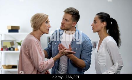 Junger Mann Beilegung von Konflikten zwischen Mutter und Ehefrau, familiäre Probleme, Streit Stockfoto