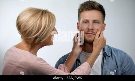 Mutter kneifen Wangen irritiert erwachsener Sohn, unabhängiges Leben problem Konzept Stockfoto