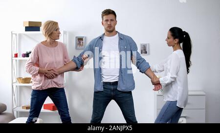 Mutter und Ehefrau ziehen junge Menschen in verschiedenen Richtungen, Konflikte in der Familie Stockfoto