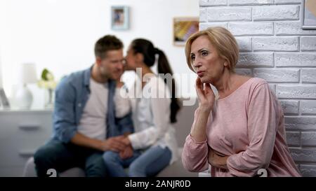 Neugierig Schwiegermutter heimlich zuhören Frau whispering Secret auf Mann Ohr Stockfoto