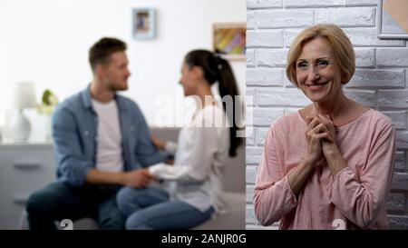 Glücklich lächelnde Schwiegermutter beobachten junge Paar Versöhnung nach Streit Stockfoto