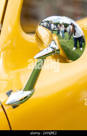 Nahaufnahme des verchromten Außenspiegels eines gelben amerikanischen Oldtimers auf der Oldtimer-Show Stockfoto