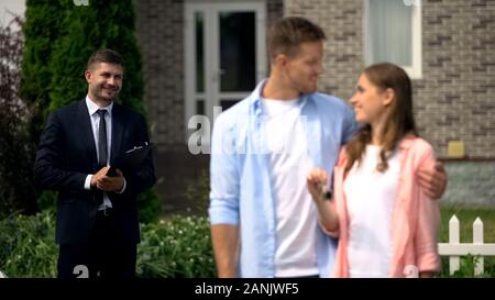 Immobilienmakler beobachten glücklich Paar beim neuen Haus zeigt die Tasten an der Kamera Stockfoto