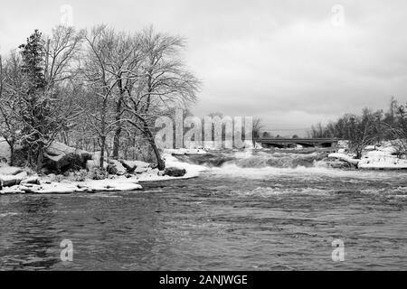 Eine Schneedecke deckt die Felsen und Bäume in dieser schwarz-weiß Ansicht von Burleigh Falls, Ontario Stockfoto