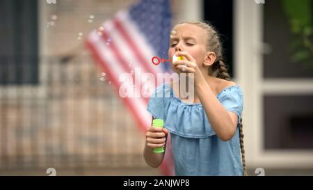 Positive Mädchen bläst Seifenblasen, sorglose und glückliche Kindheit, Freizeit Stockfoto