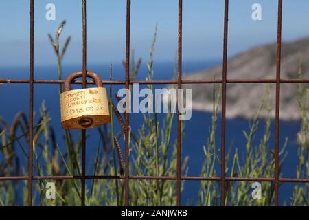 Romantisches Liebesschloss oder Liebesschloss, am Zaun mit Blick auf die Küste in Zakynthos, Griechenland befestigt Stockfoto