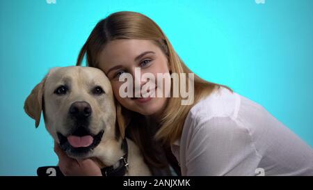 Lächelnde Frau umarmt süße Labrador Hund, Kamera, pet ist der beste Freund Stockfoto