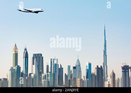 Kommerzielle Flugzeug Fliegen über moderne Dubai Wolkenkratzer gegen den klaren blauen Himmel Stockfoto
