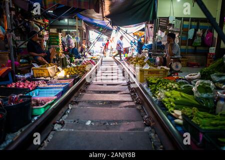 Mae Klong/Thailand-08December2019: Mae Klong Bahnhof mit Gleisen und Zügen, die durch den täglichen Markt führen, mit Anbietern, die alles verkaufen. Stockfoto