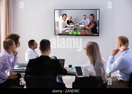 Gruppe von lächelnden Geschäftsleute in Video Konferenz Treffen mit Ihren Kolleginnen und Kollegen im Büro Stockfoto