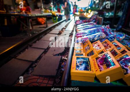 Mae Klong/Thailand-08December2019: Mae Klong Bahnhof mit Gleisen und Zügen, die durch den täglichen Markt führen, mit Anbietern, die alles verkaufen. Stockfoto