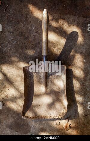 Altmodische Holz behandelt Schaufel, geschossen von oben auf einen schmutzigen Boden vergossen Stockfoto