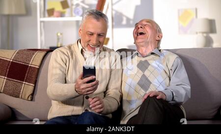 Ältere Menschen zeigen lustiges Foto auf dem Smartphone im alter Freund, Spaß zu Hause in Stockfoto