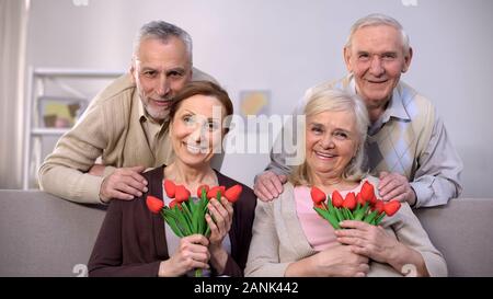 Im Alter von Paare umarmen und lächelnd auf Kamera, Frauen, die Tulpen, Feier Stockfoto