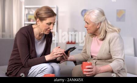 Ältere Frau mit Smartphone sitzen mit reife weibliche Freund auf dem Sofa, Freizeit Stockfoto