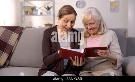 Ältere Mitschüler überprüfen Fotos im Album, lachen gemeinsam Spaß haben Stockfoto