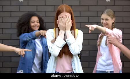 Verzweifelte weibliche Teenager für Gesicht, Hände leiden und Mobbing in der Schule Stockfoto