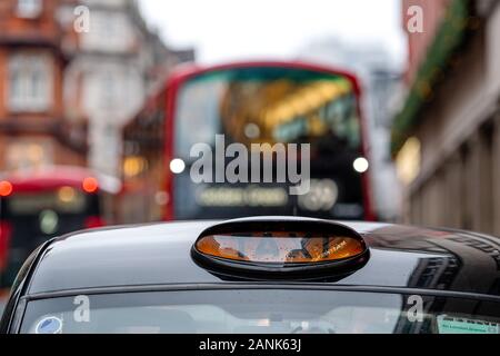 London, England, UK - 31. Dezember 2019: Ein britischer schwarzen Londoner Taxi Schild mit Defokussierten roter Bus in background-image Stockfoto