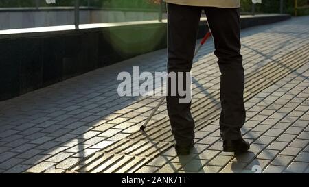 Sehbehinderten Mann mit Stock gehen auf spezielle taktiler Pflasterung für blinde Stockfoto
