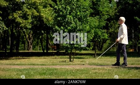 Blind Rentner sicher navigieren Sie mit weißen Stock, Wandern unabhängig in Park Stockfoto