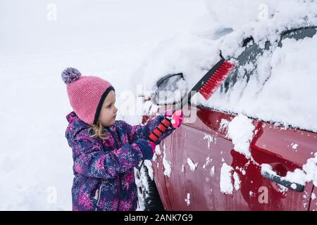 Kleines Mädchen Reinigung Auto vom Schnee Nach starker Schneefall Stockfoto