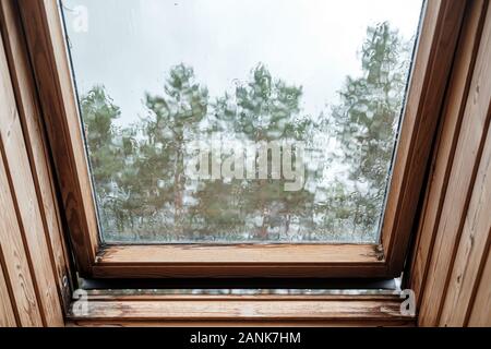 Eine offen-Dach Fenster im Dachgeschoss, mit Regentropfen Abtropfen der Glas- und verzerren das Bild. Stockfoto