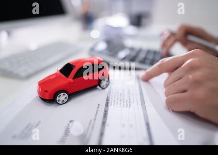 Rotes Auto Vor Geschäftsmann Berechnung Darlehen im Büro Stockfoto