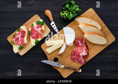 Ansicht von oben der Camembert Sandwich mit geräuchertem Speck auf dunklen Holztisch. Stockfoto